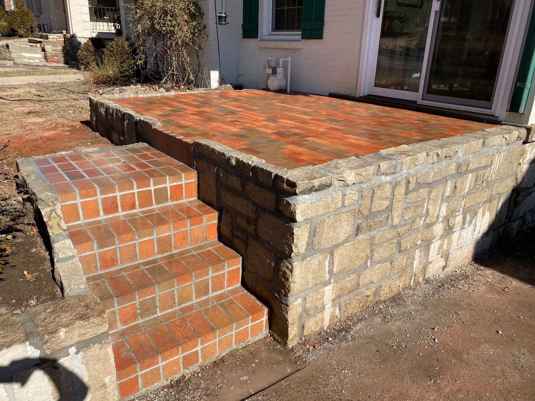 Raised brick landing with soldier-course steps and stone sidewalls