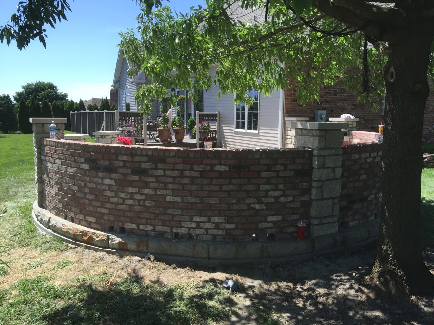 Curved brick wall with stone pillars and stone caps