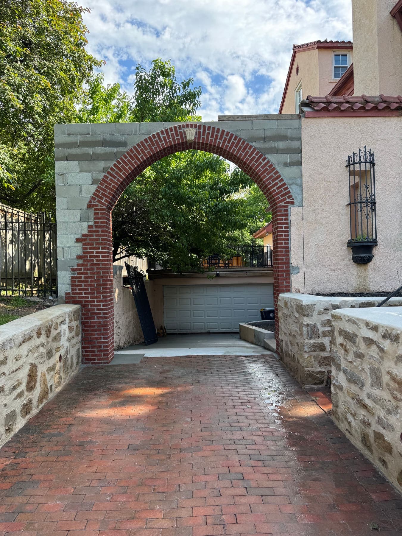 Brick arch under construction over a brick driveway, with CMU backup still showing
