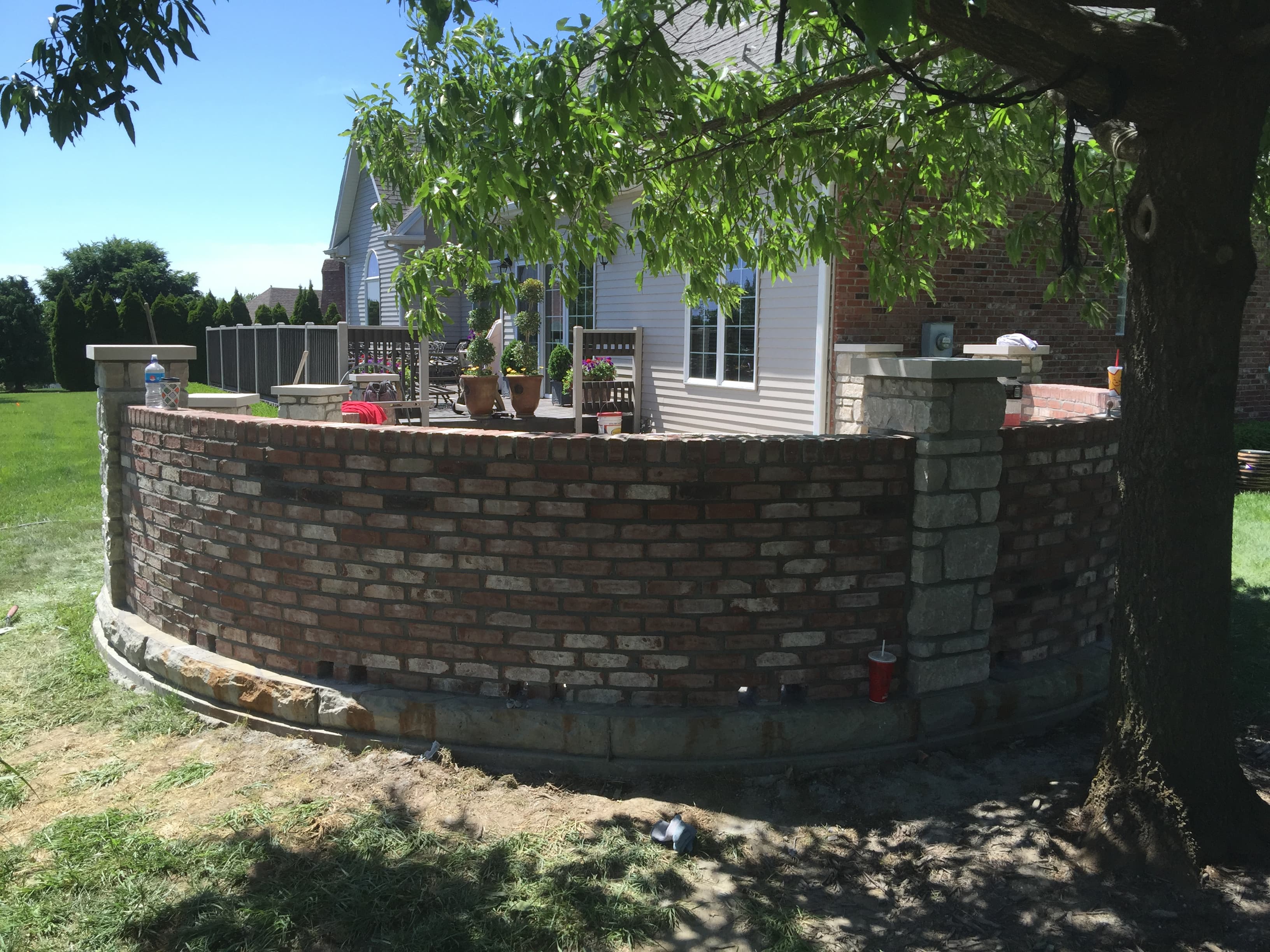 Curved brick retaining wall with stone pillars