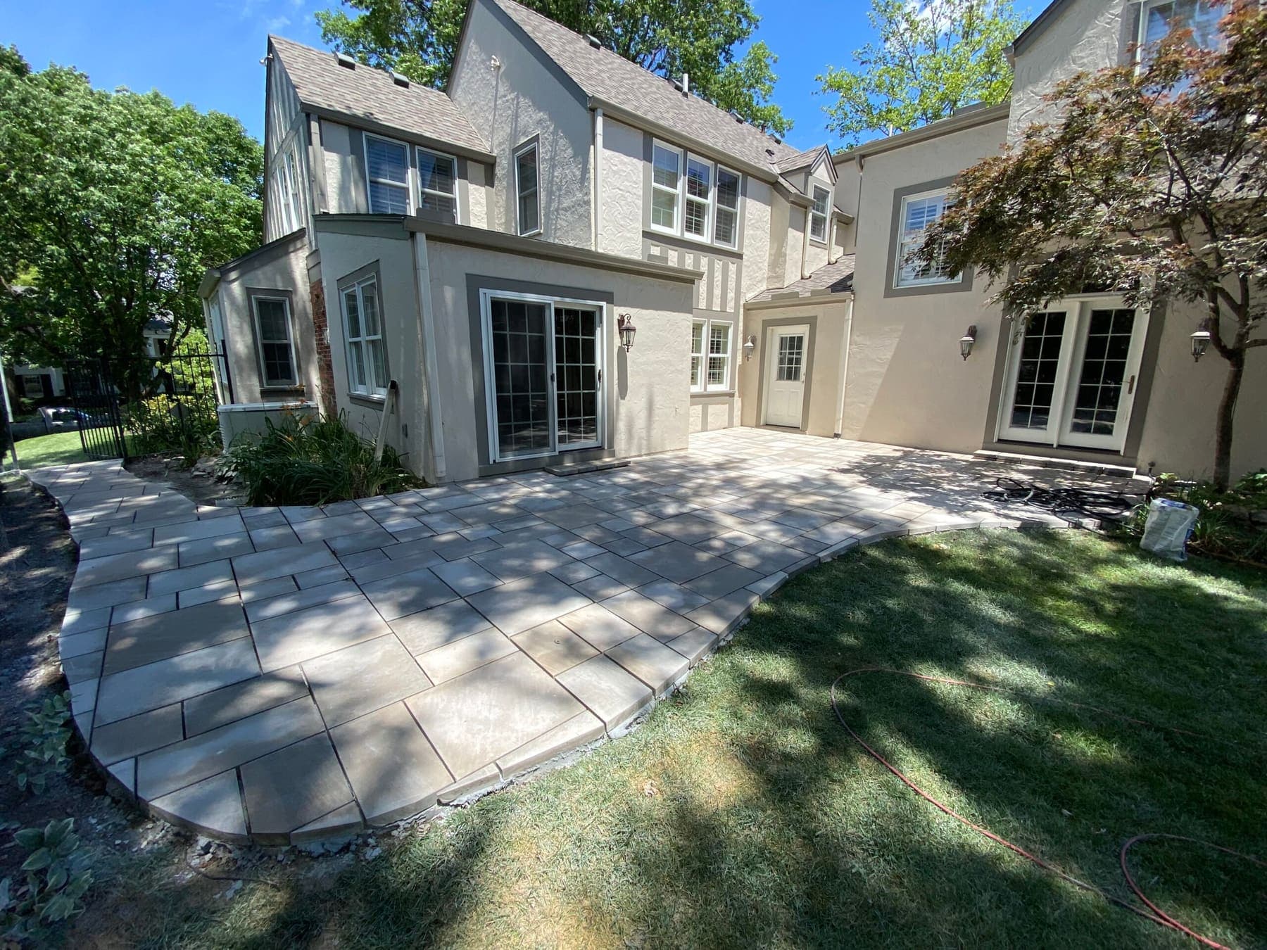Paver patio fitted to the back of a house with a matching walkway