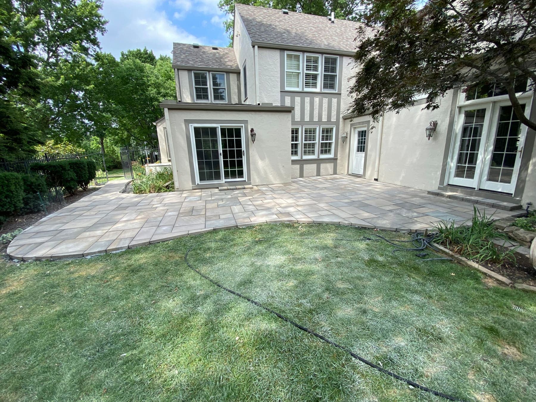 Large curved paver patio behind a two-story house