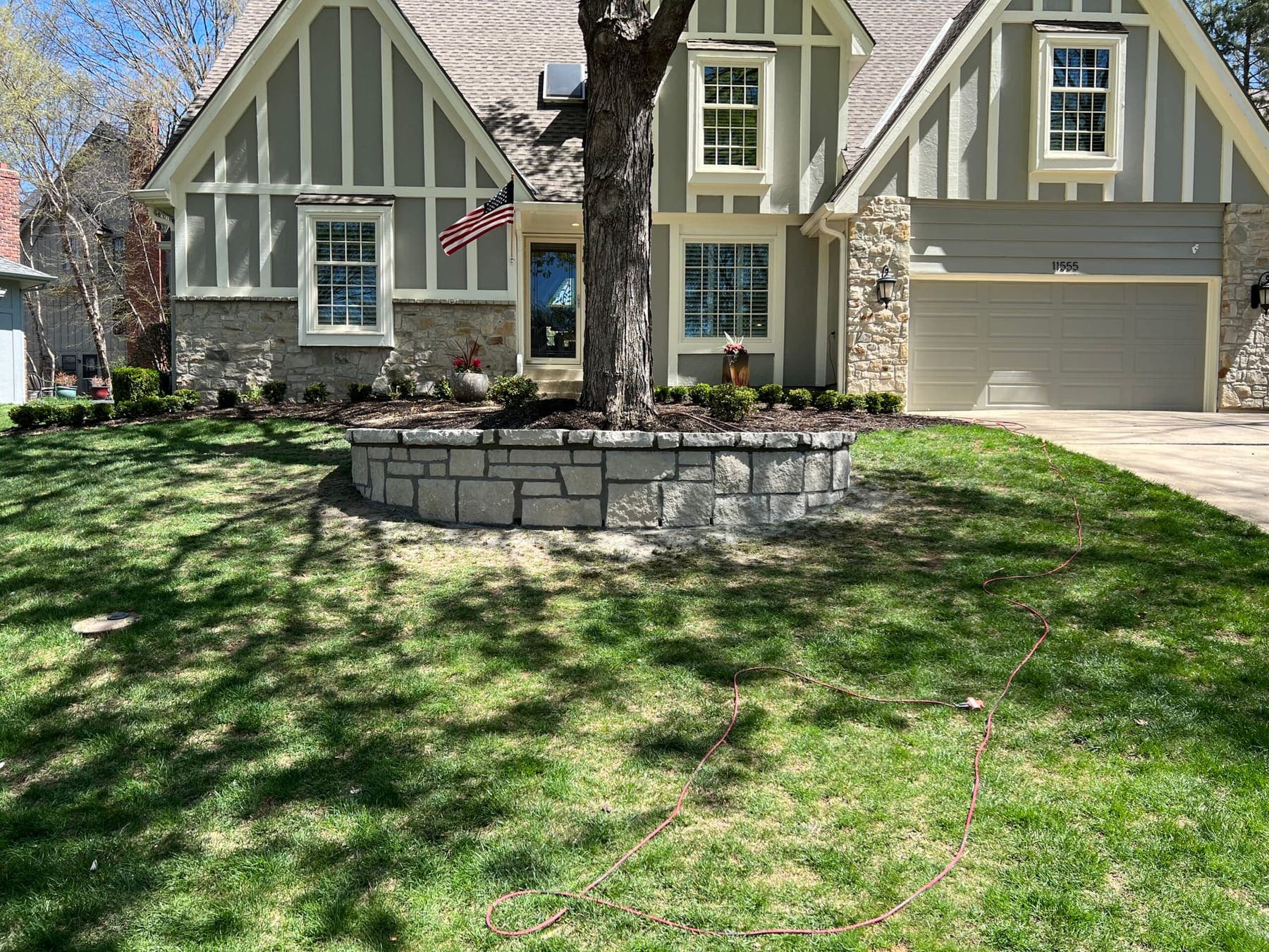 Semi-circular stone retaining wall around a front-yard tree